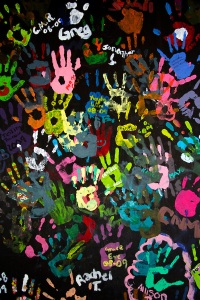 Children's colorful hand prints on black background for texture and design